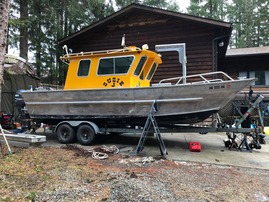 Landing craft with cabin on trailer near boat shed